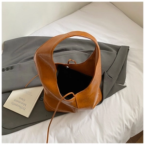Detail view of caramel faux leather tote bag showing glossy texture and drawstring closure