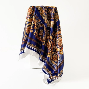 Dettaglio ravvicinato del drappeggio e della stampa barocca sul foulard di raso blu e oro