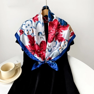 Detail of vibrant red and blue floral print silk scarf with a navy blue border