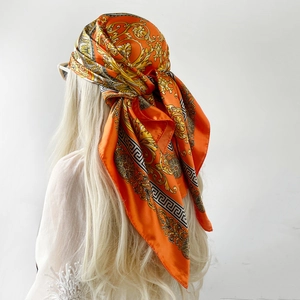 Detailansicht eines orangefarbenen Seidenschals mit goldenen Barockmustern und Mäander-Design