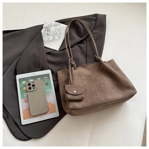 Macro view of matte dark brown tote bag featuring decorative knot and detachable mini pouch