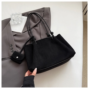 Macro view of matte black tote bag with slender knotted handles and matching coin pouch