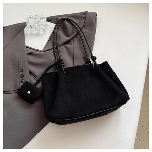 Detailed macro view of black frosted tote bag material and small matching charm pouch