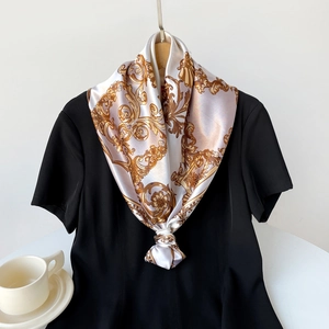 Close-up of elegant silk scarf with golden Baroque motifs and chain patterns on white