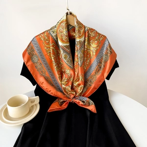 Detailansicht des orangefarbenen Barock-Seidenschals elegant geknotet an einem schwarzen Kleid
