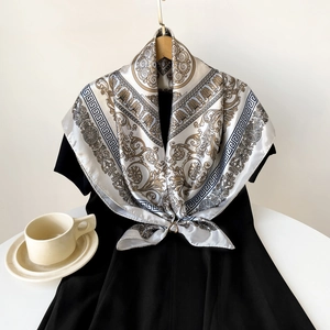Detail eines eleganten Seidenschals mit Barockdruck in Beige und Gold auf Kleid