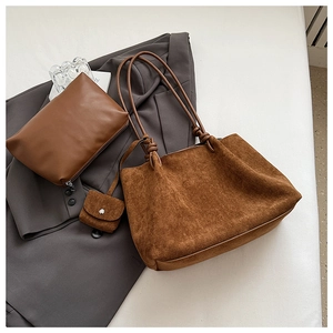 Detail of caramel suede tote bag with knotted handles and matching sub-bags on a blazer