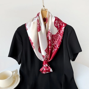 Dettaglio foulard in raso con rose rosso scuro su fondo avorio annodato su abito nero