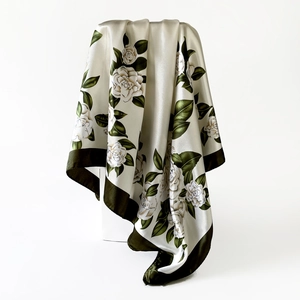 Detail of silk satin scarf with camellia floral print and deep green border accents