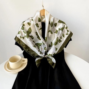 Detailed texture of satin silk scarf with elegant camellia floral print and green border