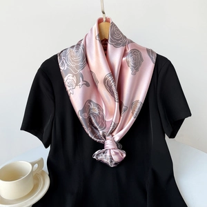 Dettaglio di sciarpa in raso rosa con stampe di rose grigie e trama setosa con nodo
