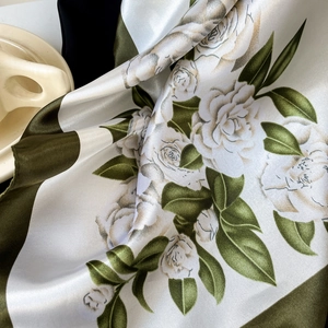 Detailed macro view of olive green and cream satin floral scarf with rose print texture