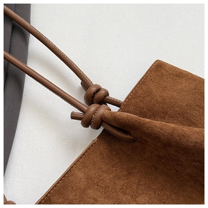 Detail shot of the brown matte suede texture and elegant knot design on the shoulder strap