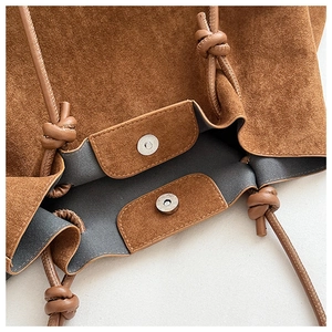 Detail of brown suede tote with double magnetic silver clasps and knotted leather strap