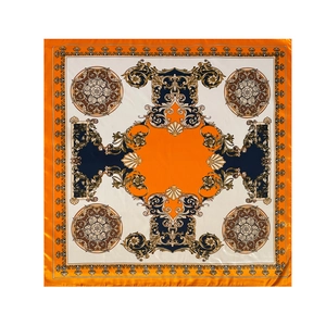 Flat lay of a satin square scarf featuring orange baroque patterns and gold floral motifs
