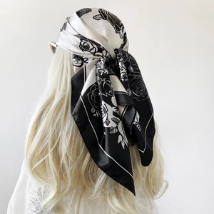 Dettaglio dell'elegante foulard quadrato in raso con stampa di rose bianche e nere