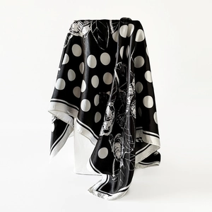 Detailed texture of black and white polka dot satin scarf with floral patterns