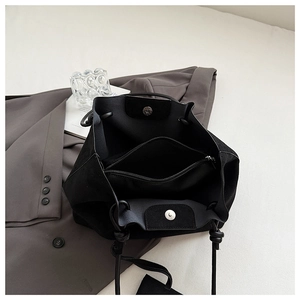 Detail of black suede tote bag showing magnetic closure and internal zipper pocket