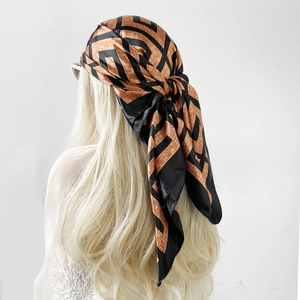 Detail of satin headscarf with orange and black geometric pattern and glossy finish