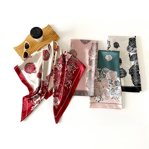 Dettaglio di foulard in seta a quadri con motivi a rose e finitura in raso liscio