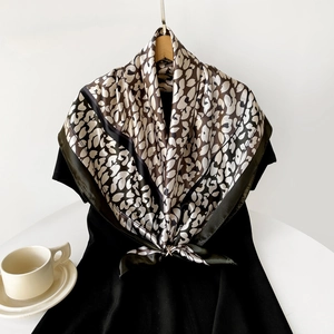 Elegant satin silk square scarf with animal print styled on a black dress and white background