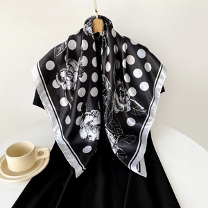 Detailed close-up of a satin square scarf with polka dots and floral patterns on a hanger
