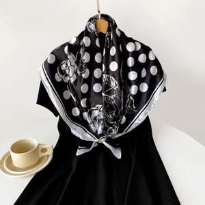 Close-up of elegant black satin square scarf with white polka dots and floral pattern