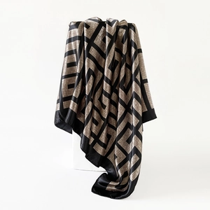 Detail of satin silk scarf showing geometric champagne gold patterns on black fabric