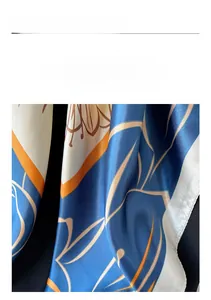 Close-up detail of smooth satin square scarf with abstract floral patterns and orange edges