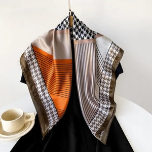 Detail of satin square scarf featuring orange geometric blocks and houndstooth pattern
