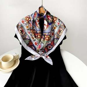 Detailed view of a vintage printed satin scarf with floral patterns on a hanger