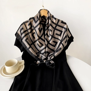 Detail of a luxury 90cm silk satin scarf with gold geometric patterns on a black dress