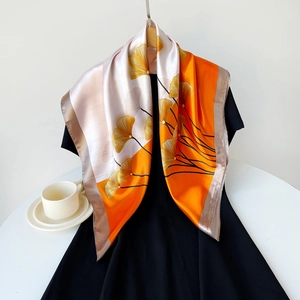 Detailed view of 90cm satin square scarf with golden ginkgo leaves on a silk-like fabric