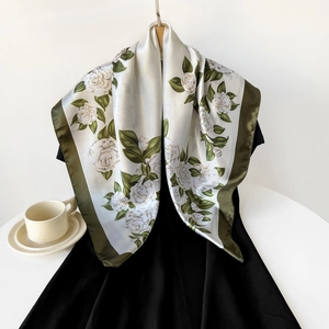 Detailed close-up of a satin square scarf with white camellia prints and green silk borders