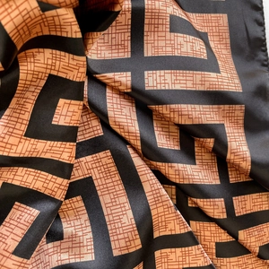 Detail of satin silk scarf showing geometric maze pattern and smooth glossy texture