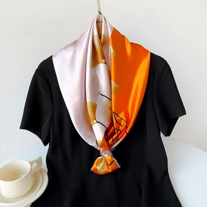 Detailed close-up of 90cm satin scarf with yellow ginkgo leaf pattern on orange and pink silk