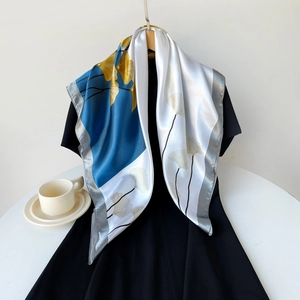 Detailed view of 90cm satin square scarf with ginkgo leaves print on black dress