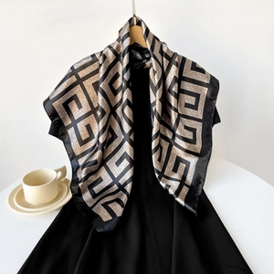 Detailed view of large satin square scarf featuring golden geometric pattern and black borders