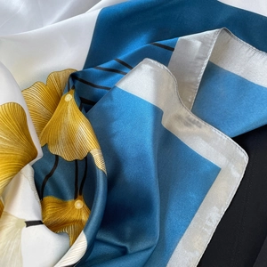 Detail of silk satin scarf showing ginkgo leaf patterns and smooth glossy texture