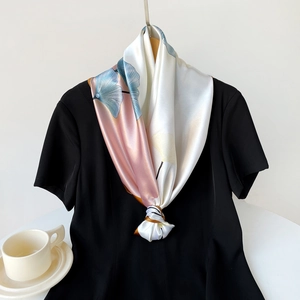 Detail of elegant ginkgo leaf print satin scarf tied on a black short sleeve dress