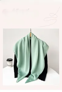 Detail of light mint green chiffon hijab draped over a black sweater on a hanger