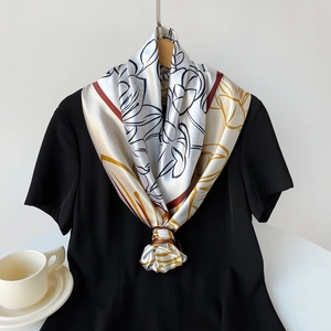 Detail of silk-satin scarf with abstract floral print tied on black t-shirt accessory