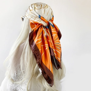 Detail of printed satin square headscarf with abstract floral pattern in orange and brown