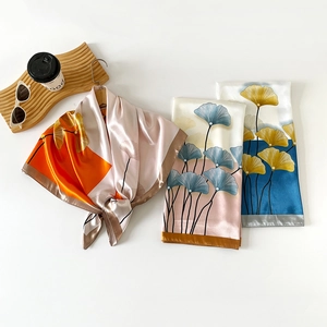 Detailed view of satin square scarves with ginkgo leaf patterns in various color palettes