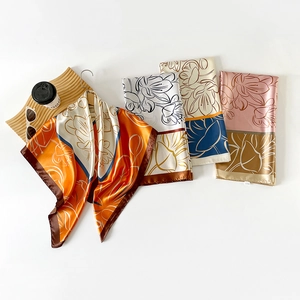 Close-up of printed satin silk square scarves with floral patterns and fashion accessories