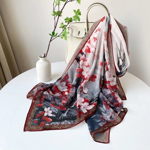 Détail d'une écharpe en satin à imprimé floral avec bordure rouge ondulée et texture soyeuse