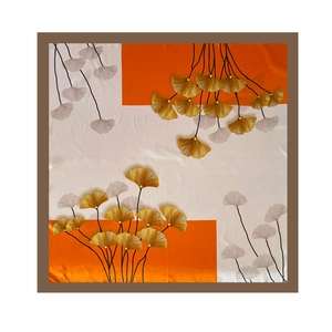 Detail of 90cm square satin silk scarf featuring orange and gold ginkgo leaf prints