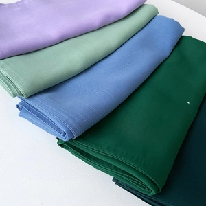 Detail of stacked multi-color lightweight scarves showing fine texture and hemmed edges