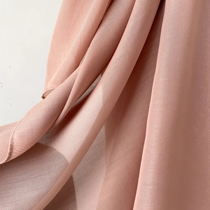 Detail shot of dusty pink chiffon fabric showing soft drape and neat stitched edges