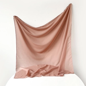 Detailed view of soft dusty pink silk scarf showing smooth satin texture and fine hemmed edges